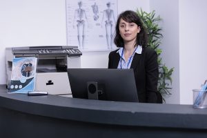 A dental office receptionist sitting behind the welcome desk.