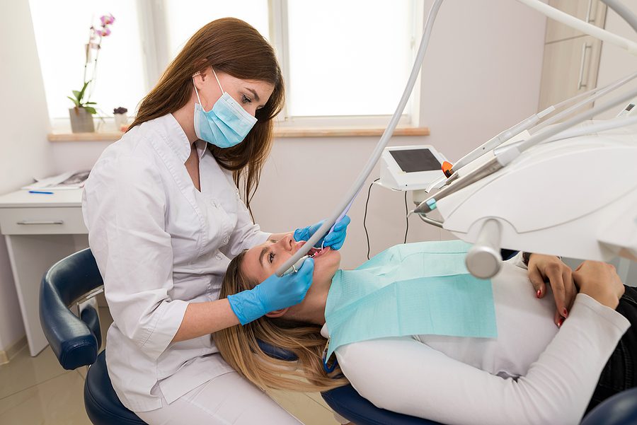 Female dental assistant examining a female patients teeth