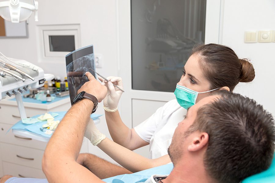 Dental assistant and patient reviewing patient x-rays during a patient appointment.