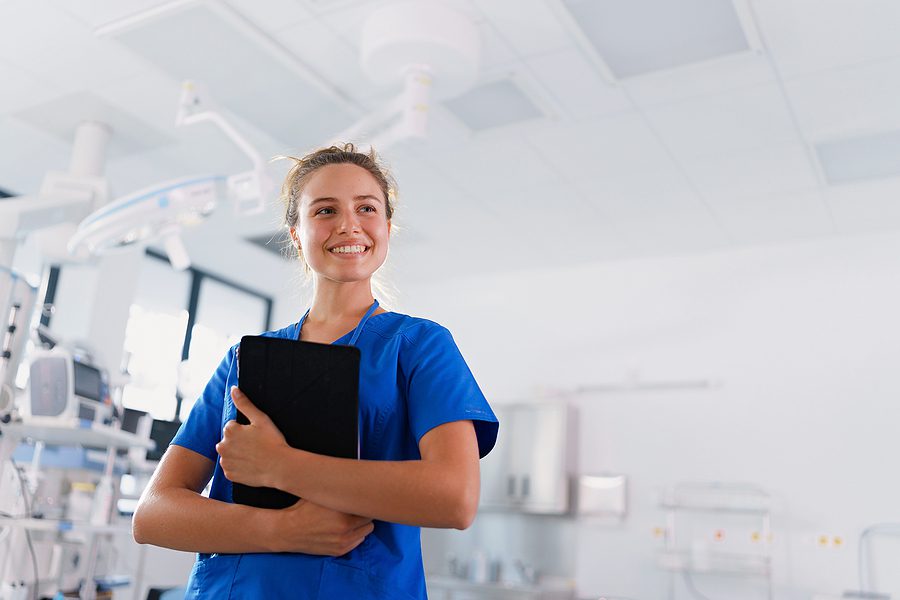 Female dental assistant holding a clipboard standing in a dental office.