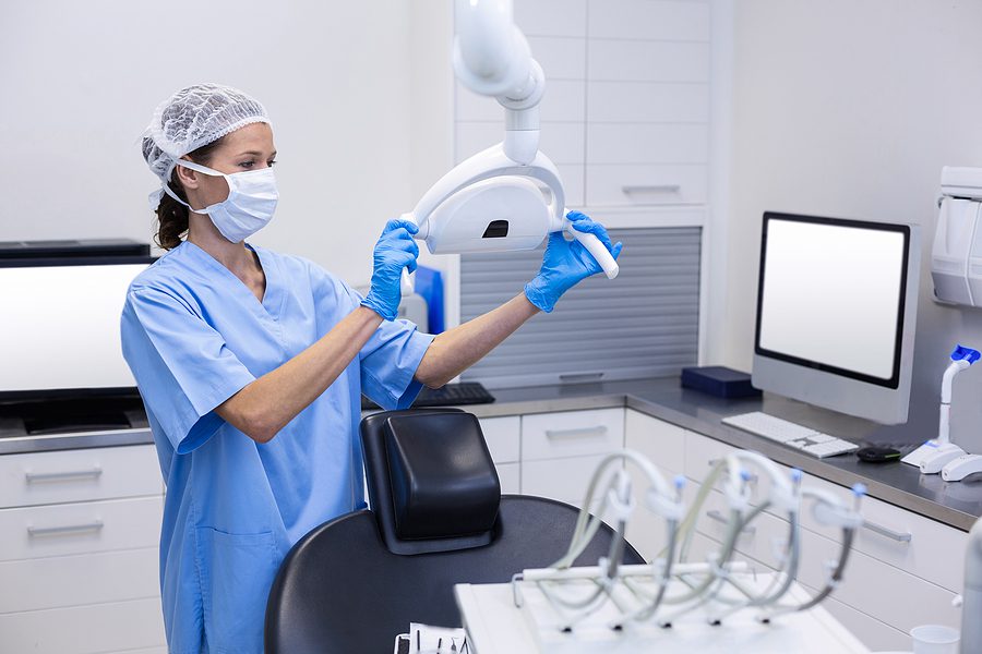 Dental assistant adjusting light in a dental clinic. 