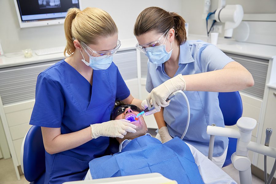 Female dental assistant and female dentist working together on a patient. 